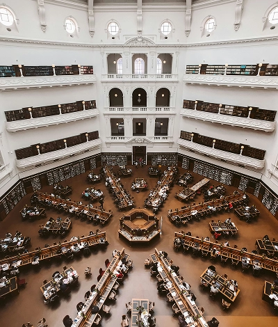 rande biblioth&egrave;que int&eacute;rieure avec plusieurs niveaux de galeries, tables d&rsquo;&eacute;tude dispos&eacute;es en &eacute;toile et lecteurs install&eacute;s