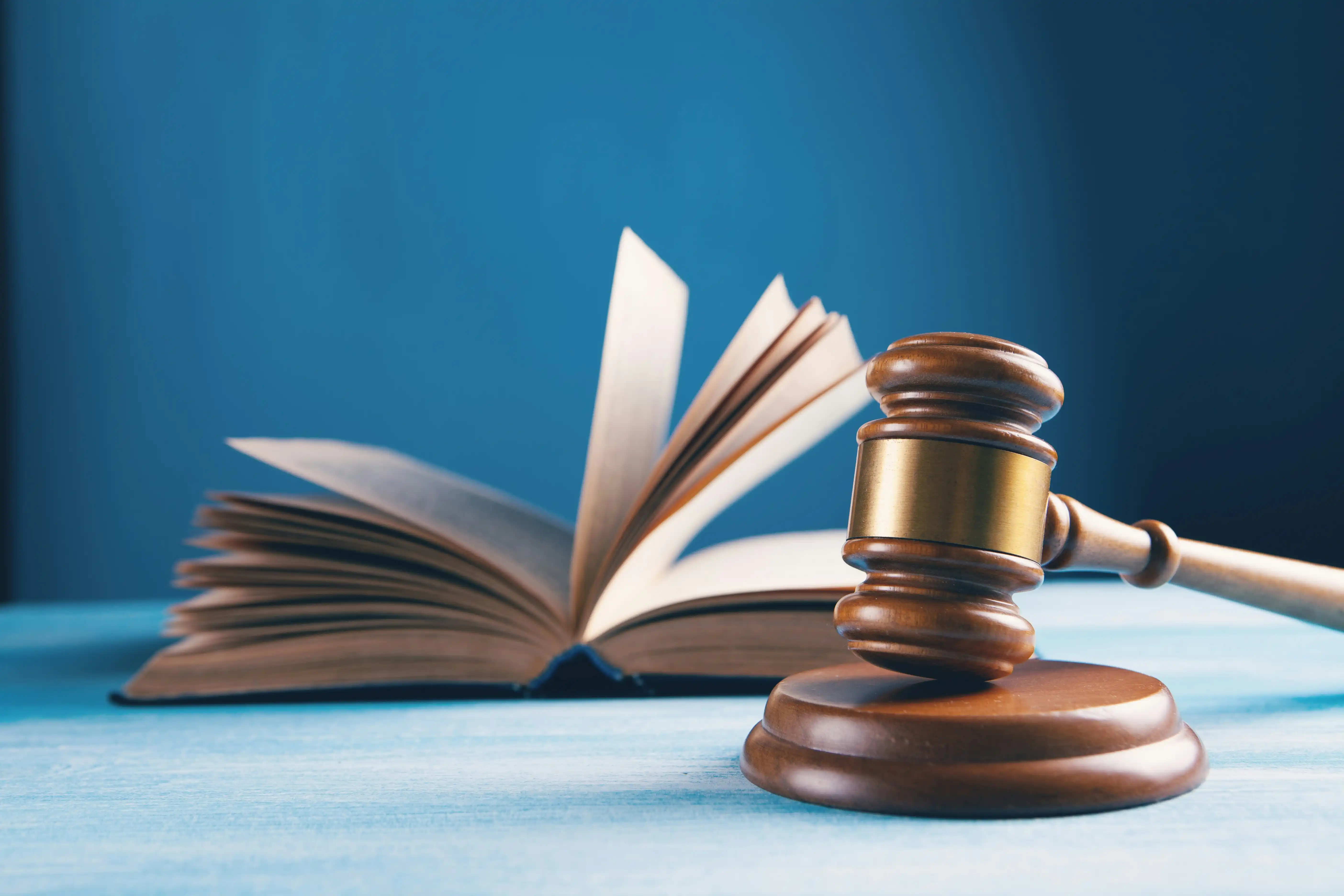 Marteau de juge et livre de droit sur fond bleu