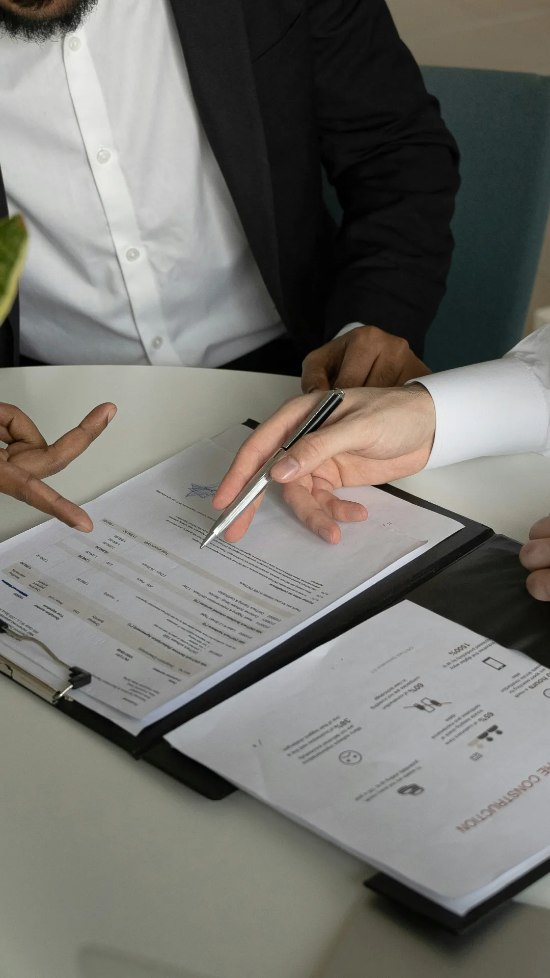 Deux personnes en costume discutant et pointant un document sur un bureau