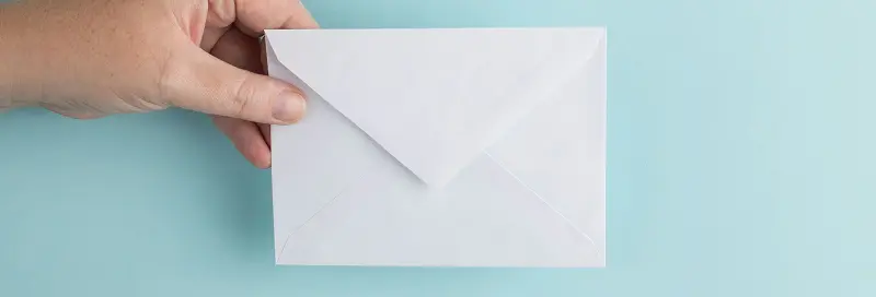 Une main tenant une enveloppe blanche sur fond bleu