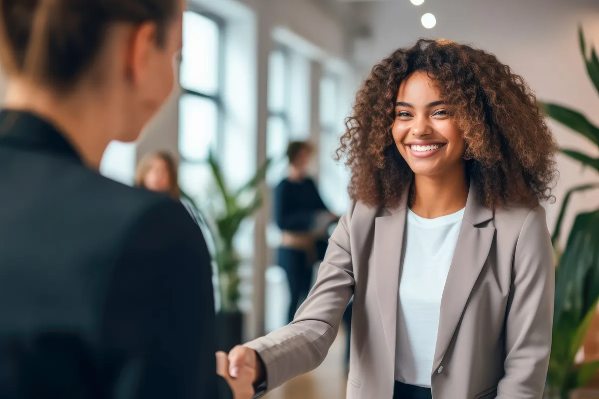 Femme souriante serrant la main d&rsquo;une personne lors d&rsquo;une rencontre professionnelle
